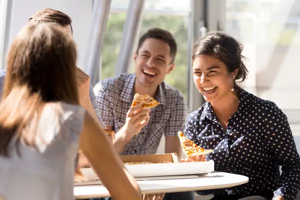 karyawan menikmati pizza di perusahaan dengan branding pemberi kerja yang baik