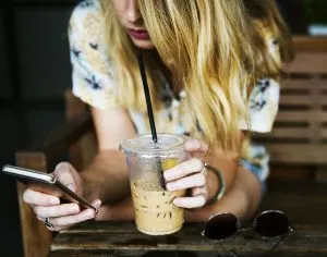 Una niña con un teléfono en la mano, explora cómo hacer que su sitio de WordPress sea compatible con dispositivos móviles.