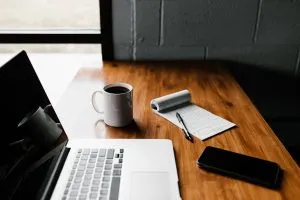 komputer laptop di sebelah secangkir kopi