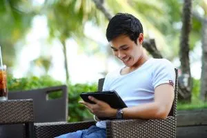 Seorang pria memegang tablet, membaca tentang hosting video di WordPress.