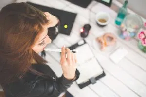 Une femme qui réfléchit aux meilleures façons d'apprendre à utiliser WordPress et de les écrire.