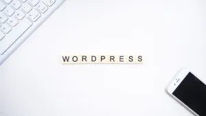 Piese cu litere care scriu „wordpress”, o tastatură albă de computer și un telefon mobil alb