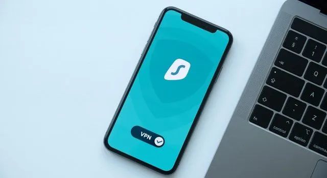 هاتف محمول على شاشة VPN بجانب جهاز كمبيوتر محمول.