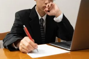 랩톱 옆에 메모를 하여 웹사이트 페이지의 형식을 적절하게 지정하는 방법에 대해 생각하고 있는 스위트룸의 작가입니다.