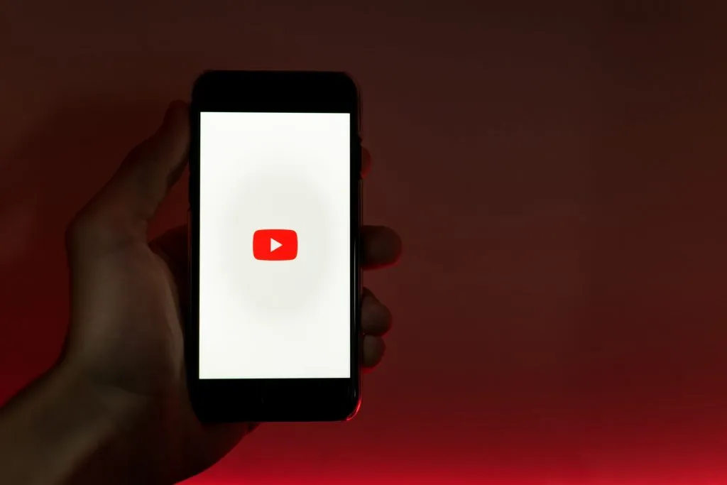 ディスプレイにYouTubeのサインが表示されている携帯電話を持っている男性。