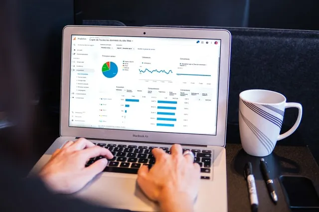Sepasang tangan di atas keyboard dengan monitor dengan metrik situs yang berbeda