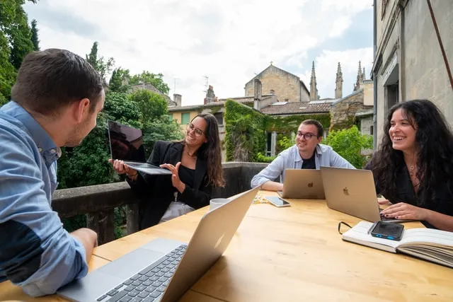 Quattro persone che si incontrano fuori e lavorano sui loro laptop