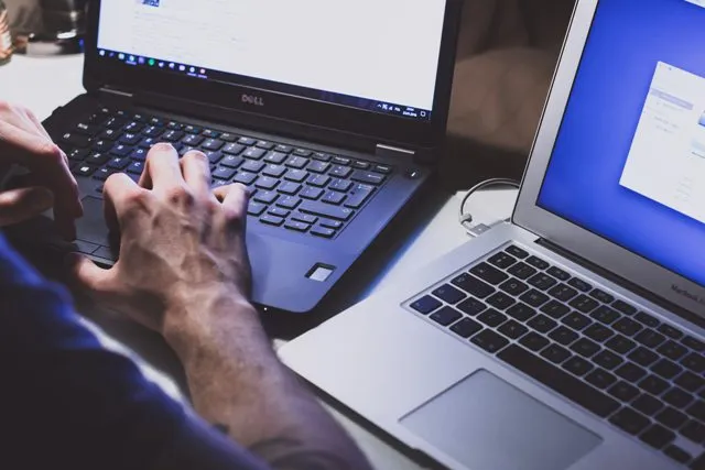 Un uomo che copia i codici da un laptop all'altro.