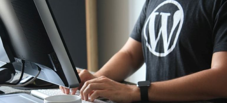 一個穿著印有 WordPress 標誌的 T 恤的人在鍵盤上打字