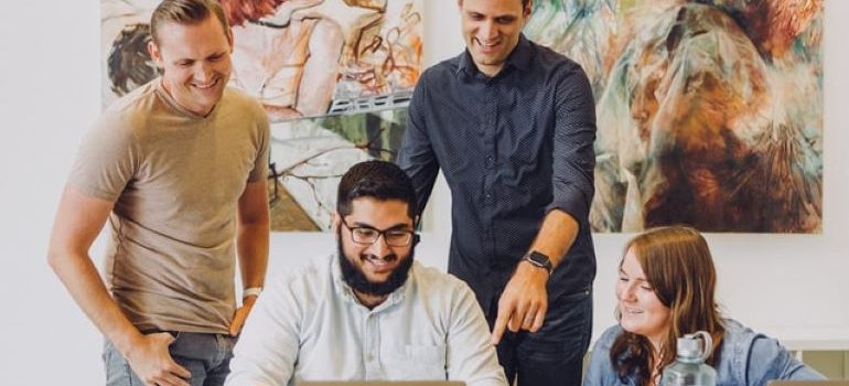 Três pessoas sorrindo e olhando para um laptop