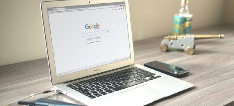 메모장과 펜 옆에 있는 나무 테이블에 있는 회색 MacBook