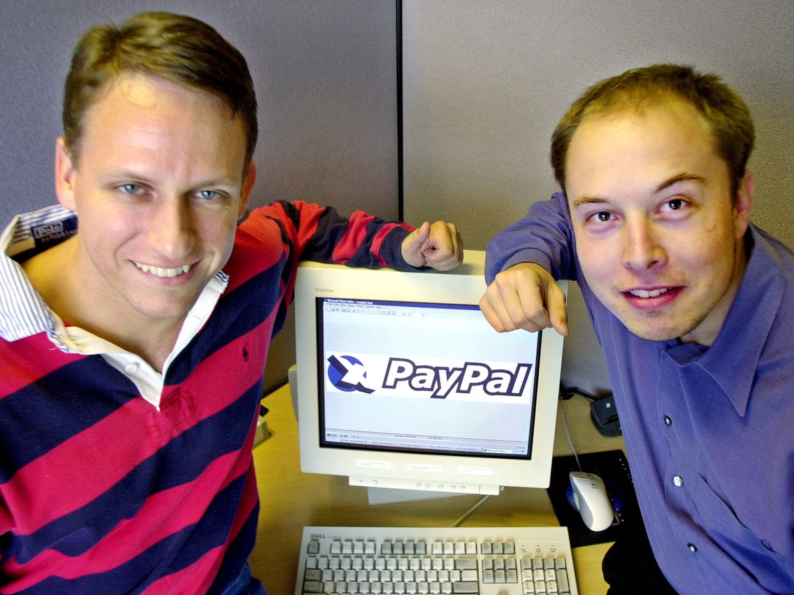 Foto de Peter Thiel e Elon Musk sentados ao redor de um computador, fundadores do PayPal.