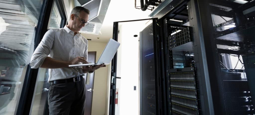 Mann mit Laptop im Serverraum