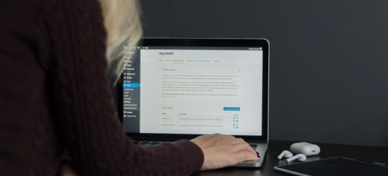 Kobieta w czarnym swetrze pracuje na swoim laptopie i próbuje dodać link do pobrania na stronie WordPress