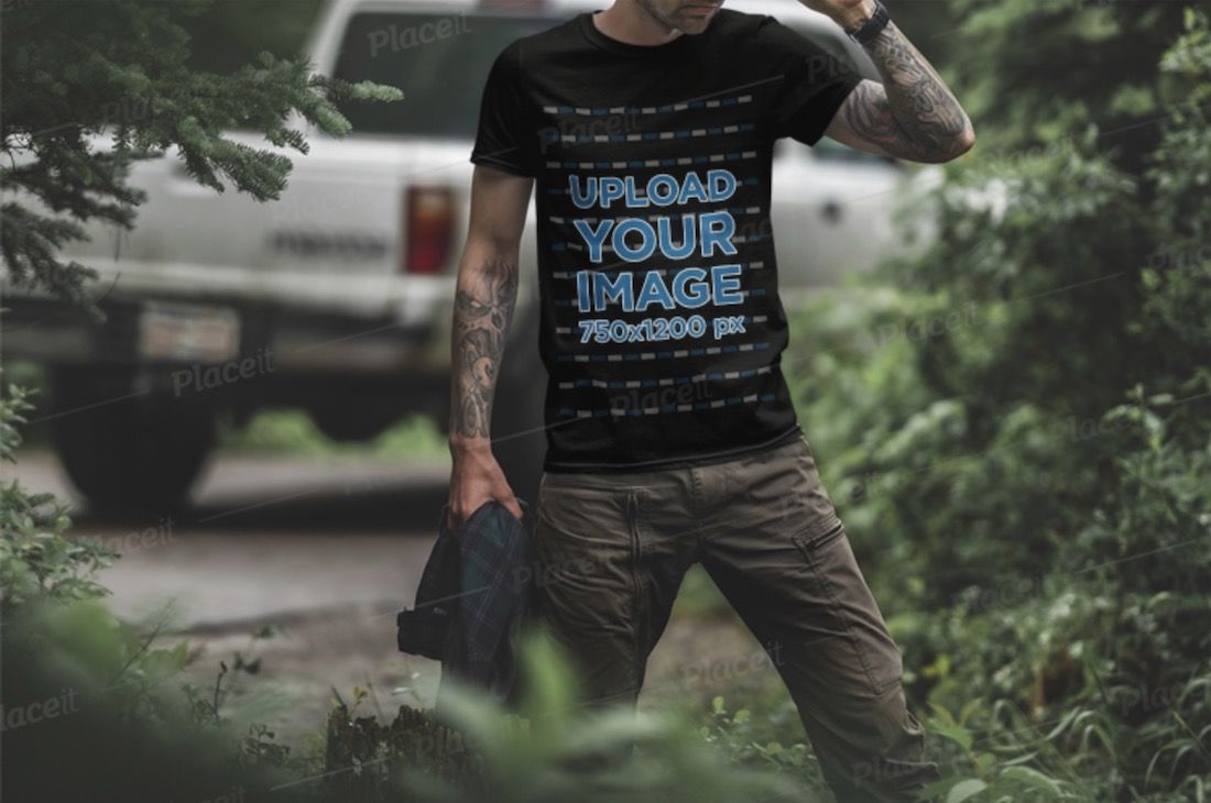 maquete de camiseta preta de um homem tatuado na floresta