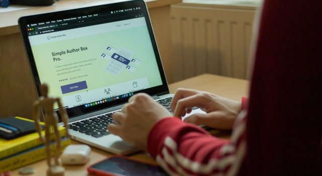 Foto orang yang sedang meneliti alat pemeriksa backlink di laptop yang diambil dari belakang